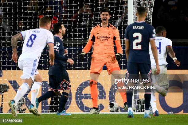 Real Madrid's Belgian goalkeeper Thibaut Courtois reacts after stoping a penalty-kick shot by Paris Saint-Germain's Argentinian forward Lionel Messi...