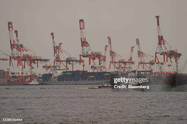 Fireboat sails past containers and gantry cranes at a shipping terminal in Yokohama, Japan,, on Monday, Feb. 14, 2022. Japan is scheduled to release...