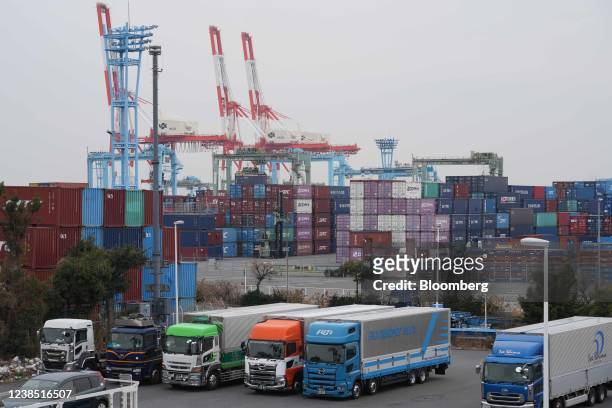 Trucks parked in front of containers at a shipping terminal in Yokohama, Japan, on Monday, Feb. 14, 2022. Japan is scheduled to release trade balance...