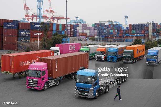Trucks parked in front of containers at a shipping terminal in Yokohama, Japan, on Monday, Feb. 14, 2022. Japan is scheduled to release trade balance...