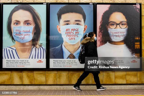 Woman wearing a face mask walks past posters reminding people to wear face masks at a subway station in Toronto, Ontario, Canada, on Feb. 14, 2022.