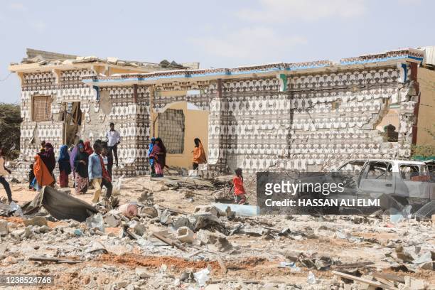 People walk next to a destroyed house and the wreckage of a car following an explosion provocked by Al-Shabaab militants' during an attacke to a...