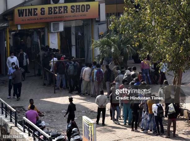 People line up for buying liquor purchasing it from a store as prices of liquor were reduced in view of the Delhi Government's new excise policy at...
