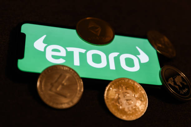 EToro logo displayed on a phone screen and representation of cryptocurrency are seen in this illustration photo taken in Krakow, Poland on February...