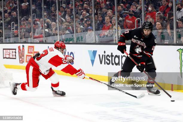 Northeastern University Huskies forward Jack Hughes keeps the puck from Boston University Terriers defenseman Domenick Fensore during the Beanpot...