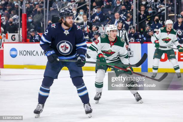 Jansen Harkins of the Winnipeg Jets and Connor Dewar of the Minnesota Wild keep an eye on the play during first period action at the Canada Life...