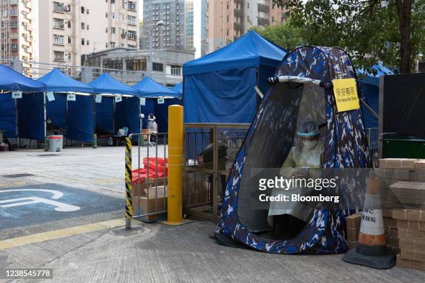 Security guard wearing personal protective equipment sits in a tent at a temporary isolation facility for patients displaying Covid-19 symptoms at...