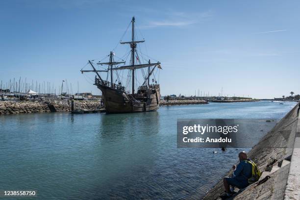 Man is sitting in the canal at the entrance to the port of Lagos with the Santa Maria ship in the background in Lagos, Portugal on February 15, 2022....