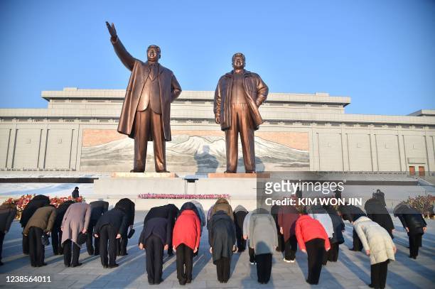 In this photo taken on February 16 people pay tribute at the bronze statues of former President Kim Il Sung and former Chairman Kim Jong Il on the...