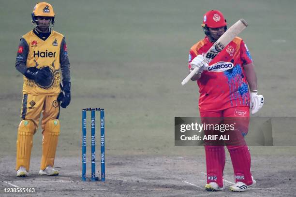 Islamabad United's Azam Khan celebrates after scoring half century as Peshawar Zalmi's wicketkeeper Mohammad Haris watches during the Pakistan Super...