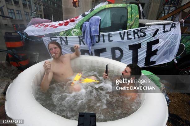 Two men sit in a hot tub as demonstrators continue to protest the vaccine mandates on February 17, 2022 in Ottawa, Canada. - Canadian police massed...