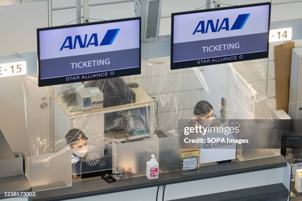 All Nippon Airways employees work behind a plastic sheet at the check-in counters inside the International Terminal of Haneda Airport. Japans Prime...