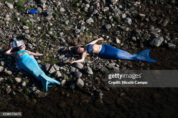 Two Extinction Rebellion activists, dressed as mermaids, protest against climate change on the dry land emerged from shallow waters of the river Po...