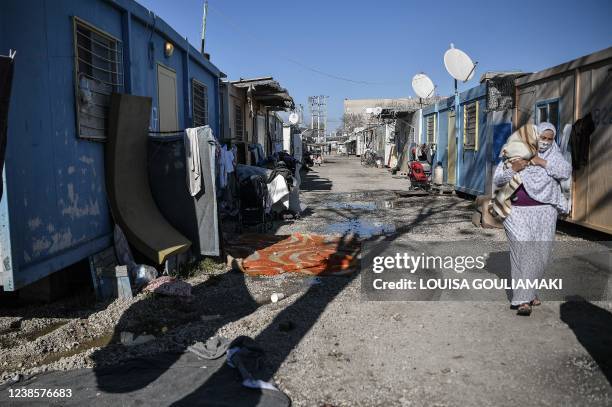 Woman carries her baby at Eleonas refugee camp in Athens on February 9, 2022. - Greece has granted refugee status to over 68,000 people in the past...