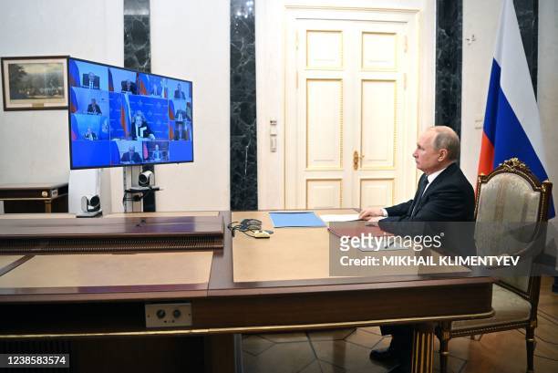Russian President Vladimir Putin chairs a meeting with members of the Security Council via teleconference call at the Novo-Ogaryovo state residence...