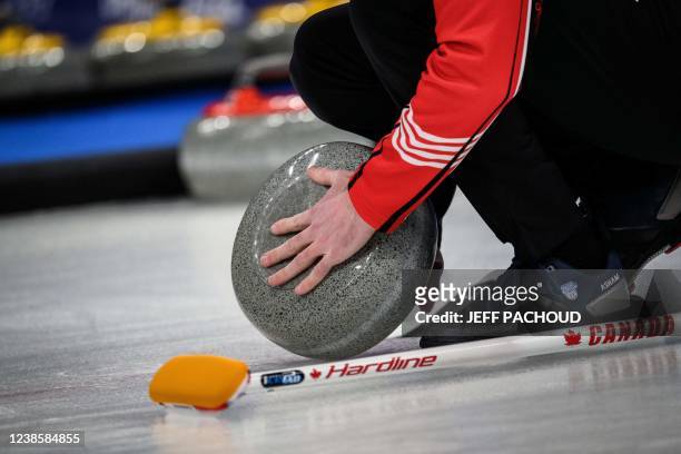 Canada team member checks on the curling stone during the men's bronze medal game of the Beijing 2022 Winter Olympic Games curling competition...