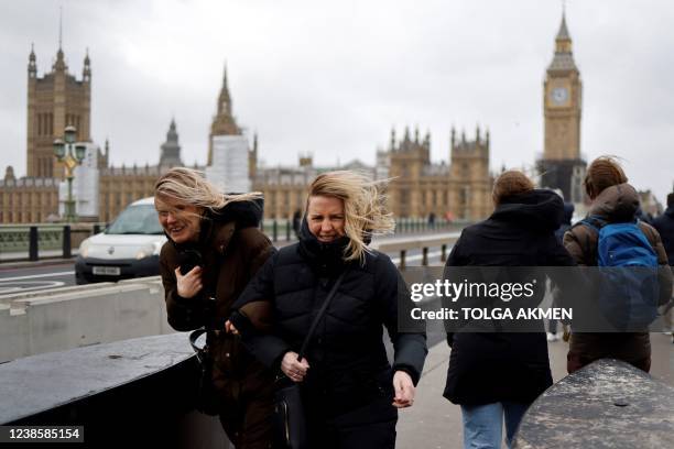 People struggle in the wind as they walk across Westminster Bridge, near the Houses of Parliament in central London, on February 18 as Storm Eunice...