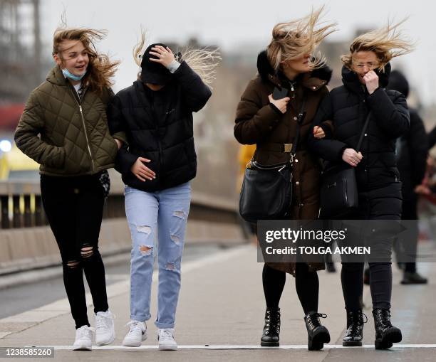 People struggle in the wind as they walk across Westminster Bridge, in central London, on February 18 as Storm Eunice brings high winds across the...