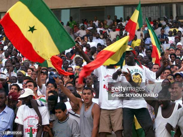 Supporters holding Senegalese flags celebrate the the victory of their national team 21 July 2001 near the Presidential Palace in Dakar. Senegal...