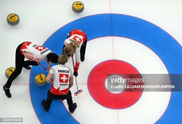 Switzerland's Esther Neuenschwander sweeps as Melanie Barbezat and Silvana Tirinzoni look on during the women's semifinal game of the Beijing 2022...
