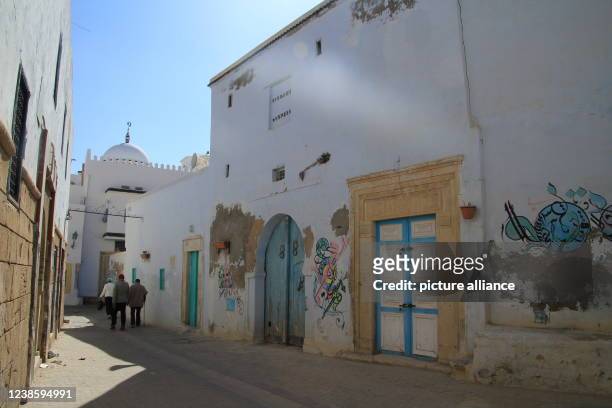 October 2021, Tunisia, Kairouan: Men walk along a street in Kairouan. Kairouan is considered the fourth holiest place in Islam after Mecca, Medina...