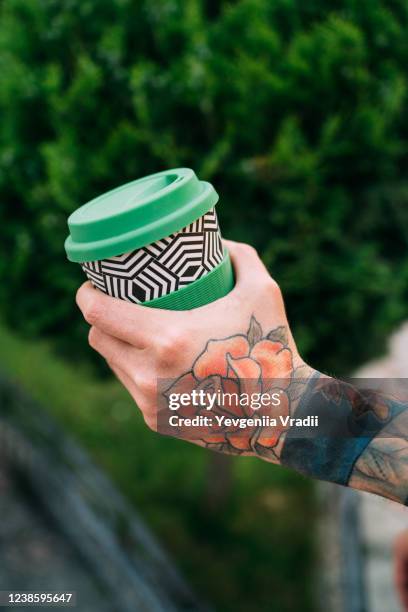 reusable coffee cup in hand - black rose tattoo designs stock pictures, royalty-free photos & images