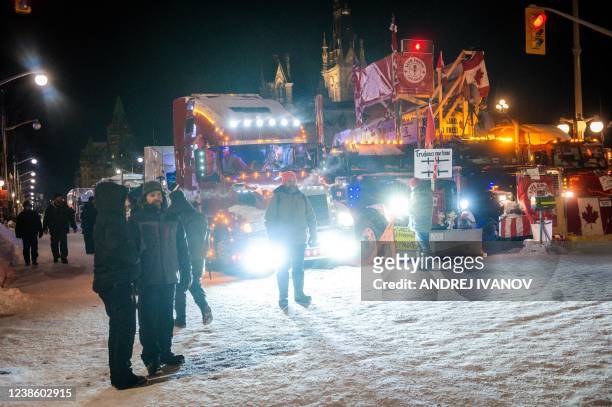 People stand near a truck at Parliament Hill during a trucker-led protest over pandemic health rules and the Trudeau government, in Ottawa on...