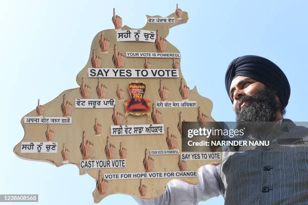 An artist holds an artwork made by him, a map of Indias Punjab state, as a part of awareness campaign on the eve of Punjab state assembly elections...