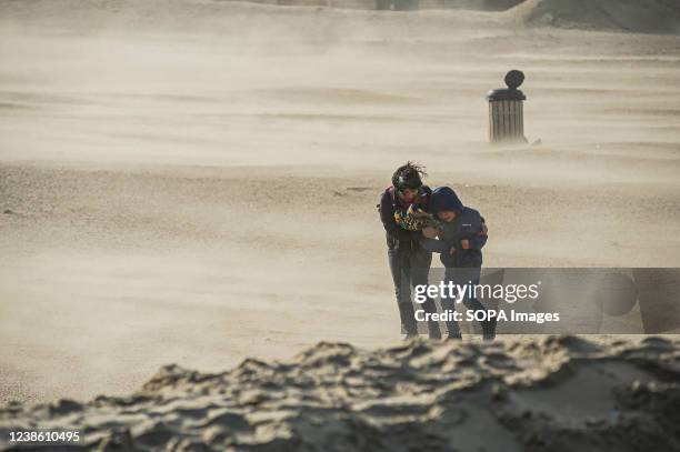 Woman helps a child through the strong gust of wind at the Dutch beach resort of Scheveningen, in The Hague, as Storm Eunice arrives from the UK....