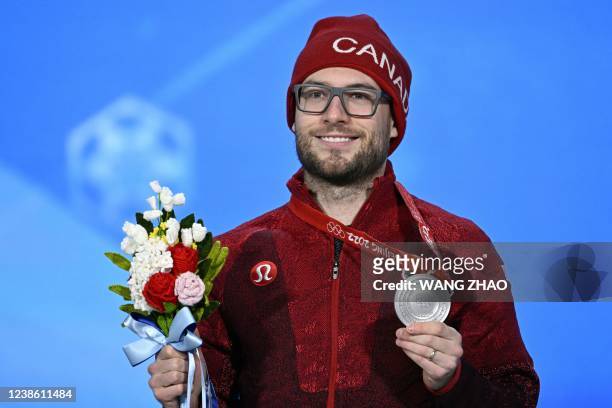 Silver medallist Canada's Laurent Dubreuil poses with his medal on the podium during the men's speed skating 1000m victory ceremony of the Beijing...