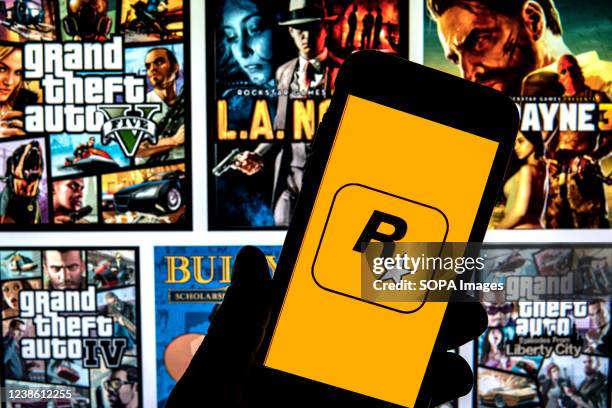 In this photo illustration a Rockstar Games logo seen displayed on a smartphone with video games cover in the background.