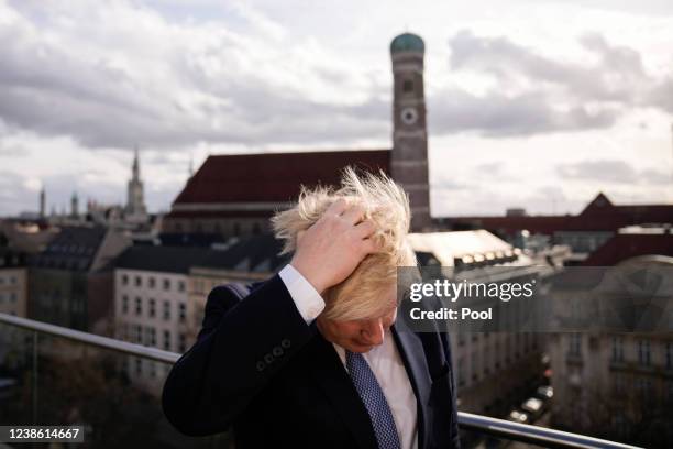 British Prime Minister Boris Johnson ruffles his hair as he gets ready to brief the media during the 2022 Munich Security Conference on February 19,...