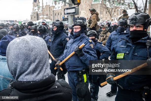 Police face demonstrators as they attempt to remove them on February 19 in Ottawa, Canada. - Police in Canada deployed to dislodge the final truckers...
