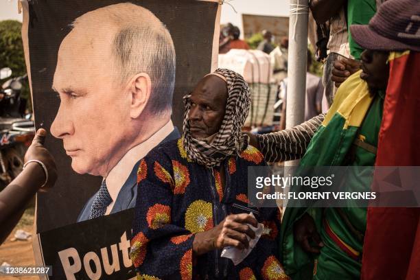 An man sits in front of a portrait of Russian President Vladimir Putin during a demonstration organised by the pan-Africanst platform Yerewolo to...