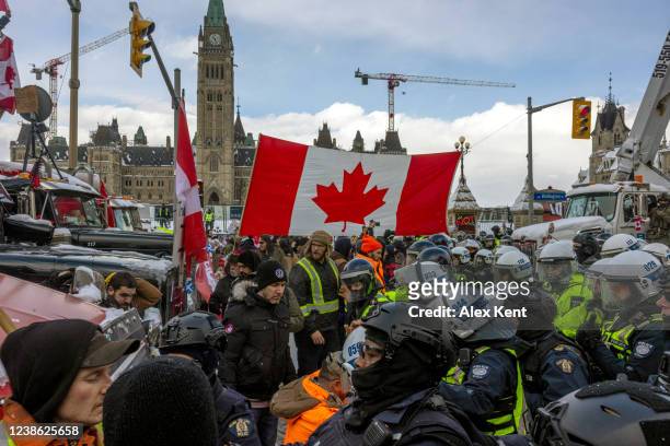 Police face off with demonstrators participating in a protest organized by truck drivers opposing vaccine mandates on Wellington St. On February 19,...