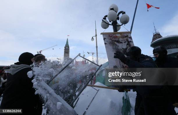 Table is flipped sending snow on protesters as police including the RCMP clear Wellington Street in front of Parliament. Protesters from the "Freedom...