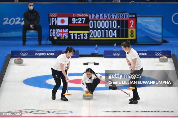 Britain's Eve Muirhead curls the stone as Britain's Hailey Duff and Britain's Jennifer Dodds prepares to sweep during the women's gold medal game of...