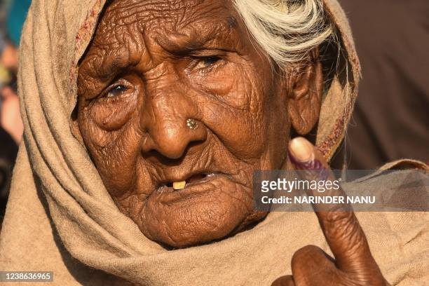 Woman shows her inked finger after casting her ballot at a polling station in a village on the outskirts of Amritsar on February 20 during the Punjab...