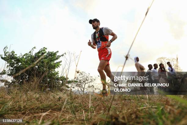 Runner competing in the 27th edition of the Mount Cameroon Race of Hope dubbed this year as "an ingredient for peace", speeds past residents...