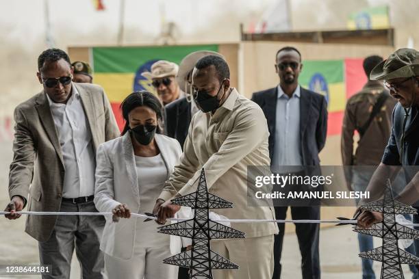 Ethiopia's Prime Minister Abiy Ahmed cuts the ribbon during the first power generation ceremony at the site of the Grand Ethiopian Renaissance Dam in...