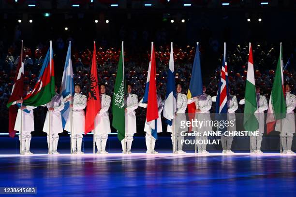 Volunteers stand with the flags of participating countries during the closing ceremony of the Beijing 2022 Winter Olympic Games, at the National...