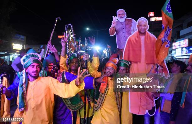 Bharatiya Janata Party supporters carry Narendra Modi and Yogi Adityanath cutouts during a road show campaign by Chief Minister Yogi Adityanath in...