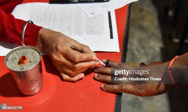 Polling officer applies indelible ink on the index finger of a voter at a polling station during the Punjab state assembly elections on February 20,...