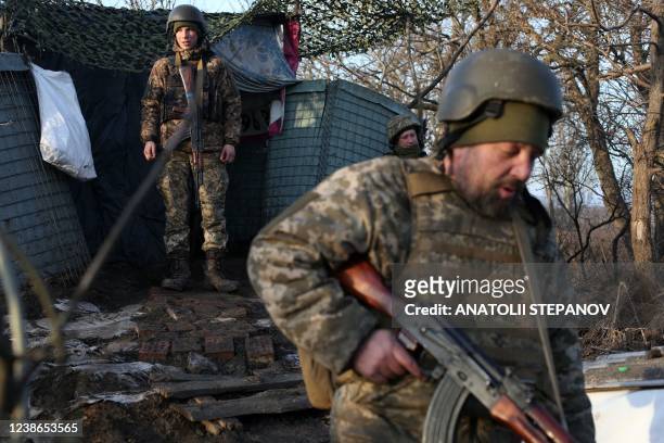 Servicemen of the Ukrainian Military Forces walk on the front line with Russian-backed separatists near Novohnativka, Donetsk region, on February 20,...