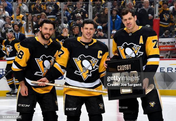 Sidney Crosby of the Pittsburgh Penguins poses for a photo with Kris Letang and Evgeni Malkin after being presented with a plaque and stick after...