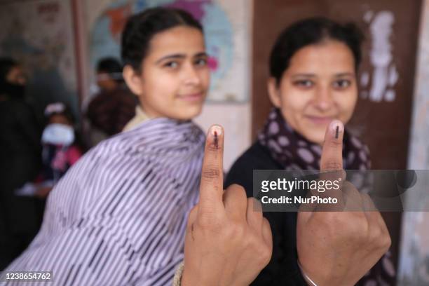 First time voters show their ink marked fingers after casting their votes for the state Assembly elections, at village Sultanwind on the outskirts of...
