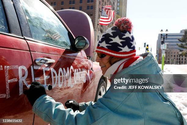 Laurie Spencer writes on a car that participated in the Lansing Freedom Convoy driving past the Michigan State Capitol in Lansing, Michigan, on...