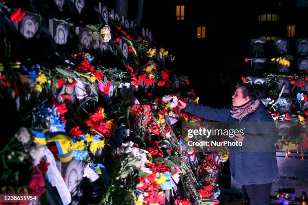 People bring flowers and candles to the monument dedicated to activists killed in anti-government protests in 2014 and named Heroes of the Heavenly...