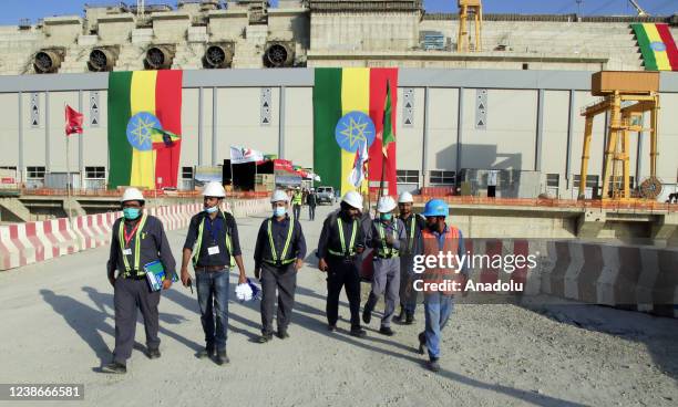 Construction team walk as Grand Ethiopian Renaissance Dam is seen behind them in Benishangul-Gumuz, Ethiopia on February 19, 2022. Ethiopia built the...