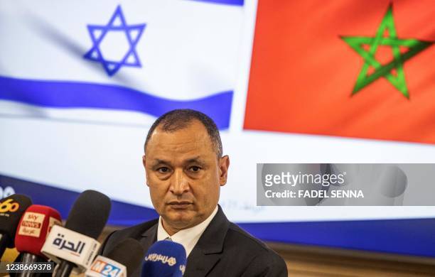 Moroccan Industry and Trade Minister Ryad Mezzour addresses the media under the flags of his country and Israel after his meeting with Israel's...